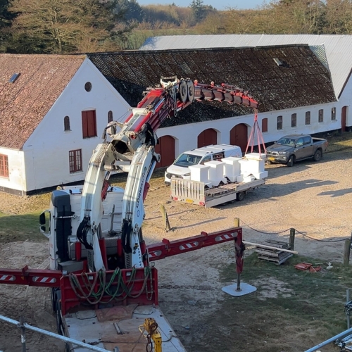 Krankørsel med løft af byggematerialer fra trailer.