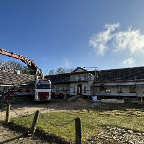 Krankørsel foran bygning under renovering med stillads.