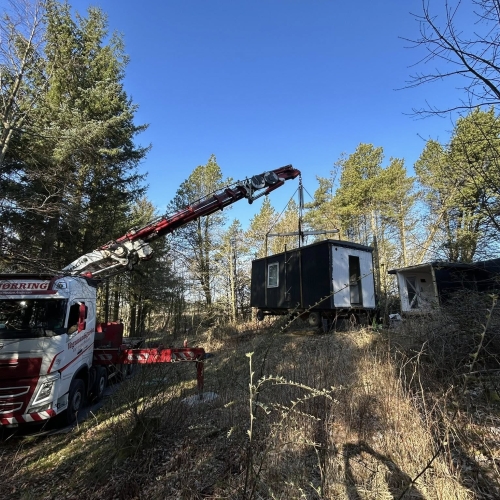 Krankørsel med sort mandskabsvogn løftet i skovområde