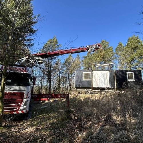 Krankørsel med mandskabsvogn placeret på skråning i skov.