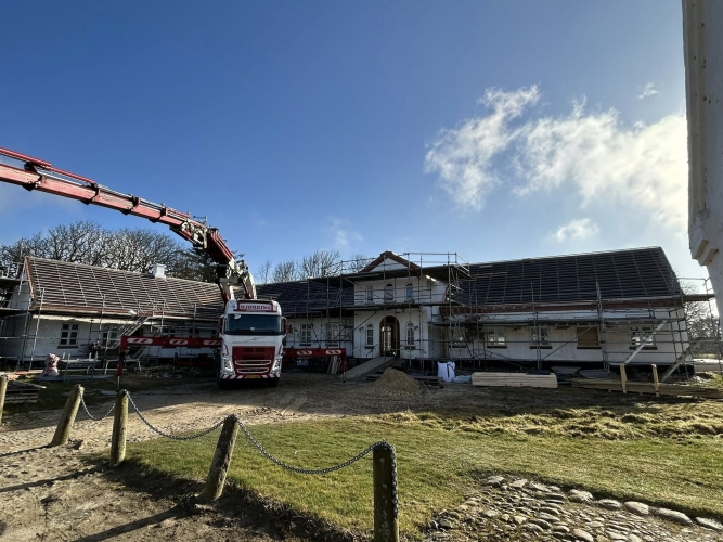 Krankørsel foran bygning under renovering med stillads.