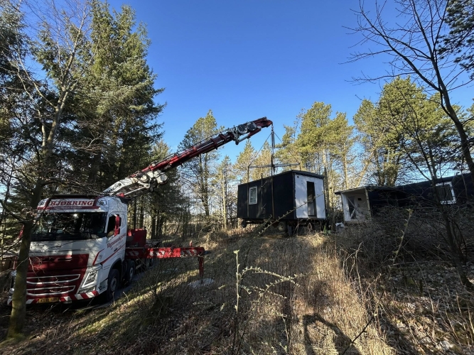 Krankørsel med sort mandskabsvogn løftet i skovområde