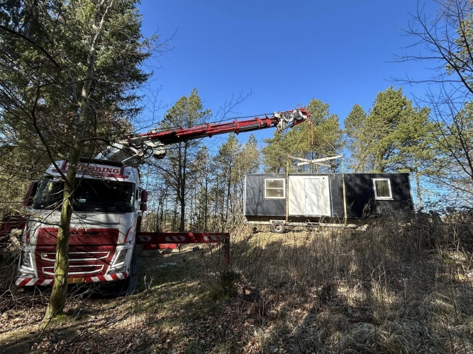 Krankørsel med mandskabsvogn placeret på skråning i skov.