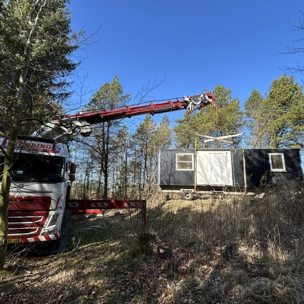 Krankørsel med mandskabsvogn placeret på skråning i skov.