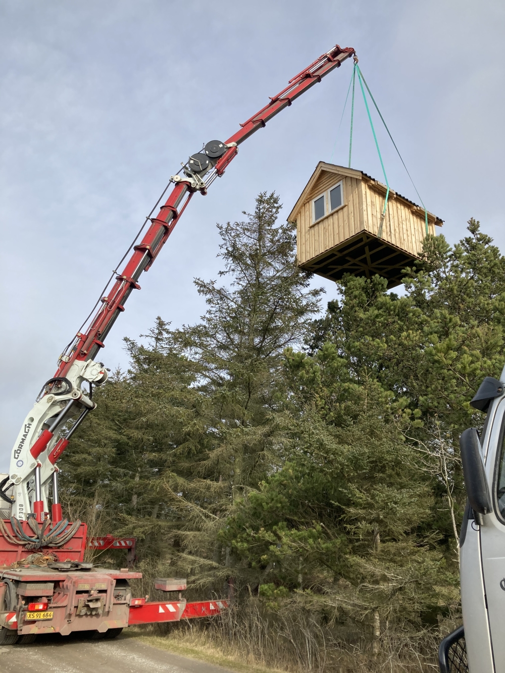 Krankørsel med løft af træhytte over trætoppene i Aalborg.